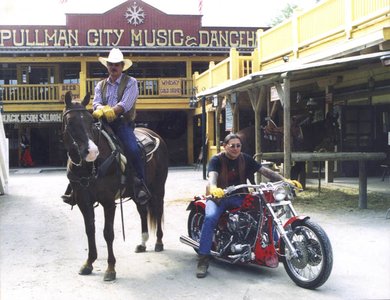 Mann in Cowboykleidung auf Pferd und Mann auf Motorrad