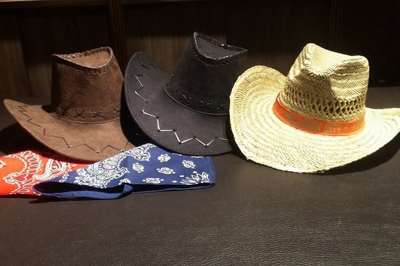Drei Cowboyhüte und zwei Tücher auf einem Tisch