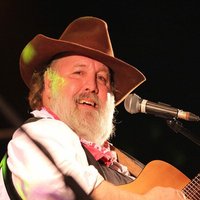 Mann in Cowboykleidung mit Gitarre